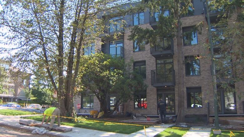 An apartment building on a street with trees. 