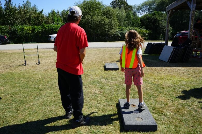 Two people playing Texas horseshoes.