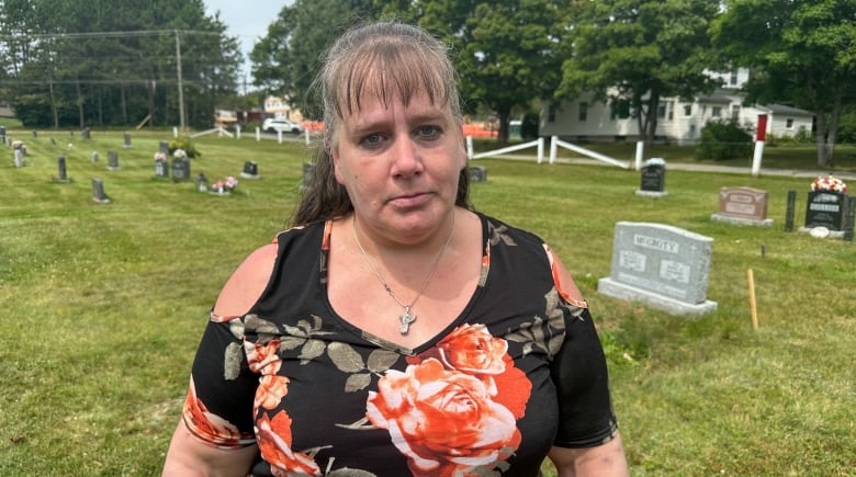 Woman looks at camera while standing in a graveyard. 