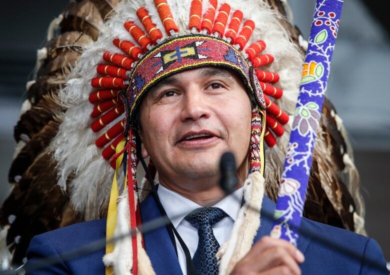 Close up of a man wearing a traditional First Nations headdress