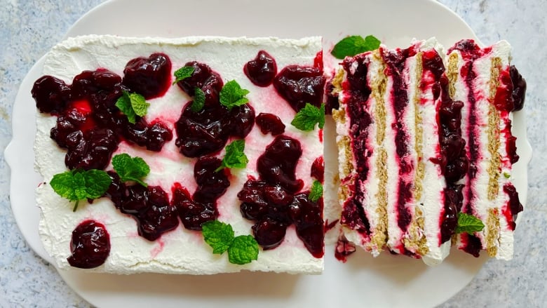 An artfully shot picture of a white cake with red cherry sauce on it.