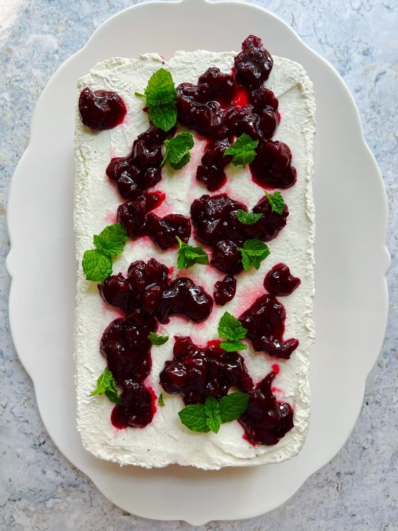 A top-down view of a white cake with cherries on it.