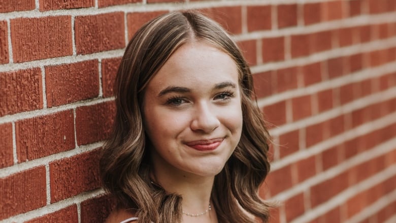 A picture of a Juliet Brennan, a young actor, leaning against a brick wall.