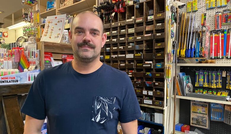 Michael Broder standing in front of colourful hardware store shelves. 