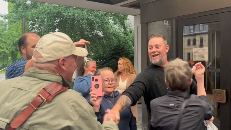 A man shaking another man's hand outside. 