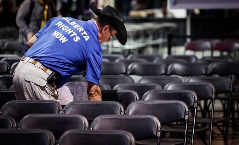 A man in a hat touches a chair in a row of chairs.