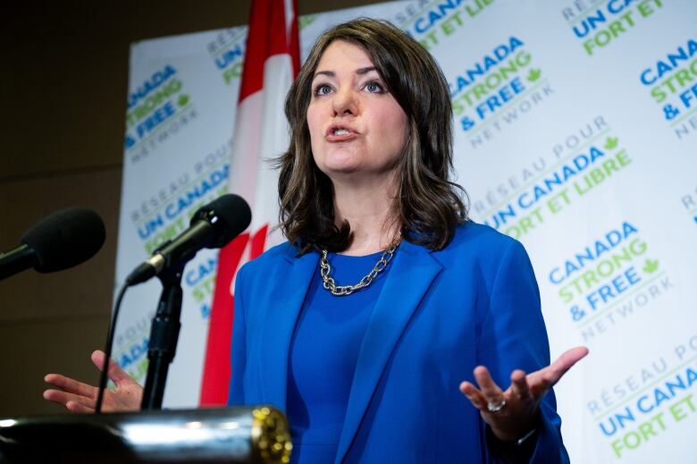 A woman gestures at a lectern.