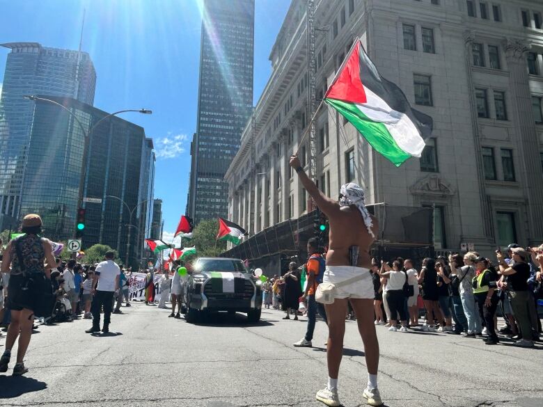 Members of a pro-Palestinian group, who are part of the Montreal Pride Parade, hold flags along the route. 