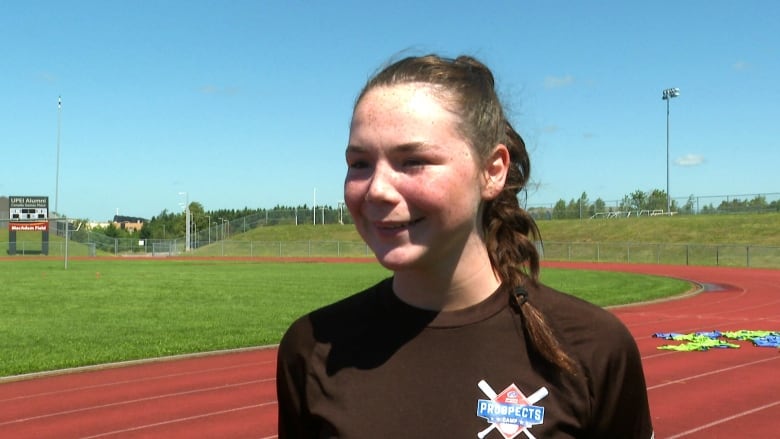 Girl in black shirt and braid on rugby field.