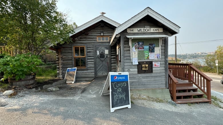 A sign outside the Wildcat Cafe indicates the restaurant is closed for repairs. The building is a log cabin.