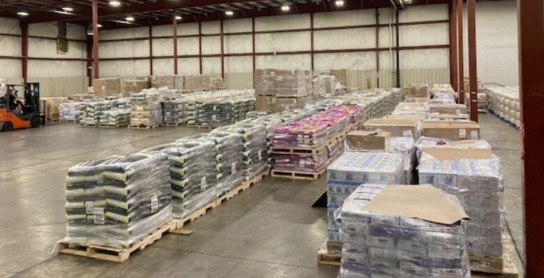 Pallets of product covered in plastic in a warehouse.