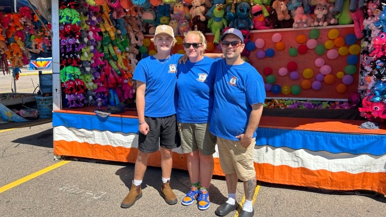 Father, mother and son wearing blue shirts standing in front of carnival game.