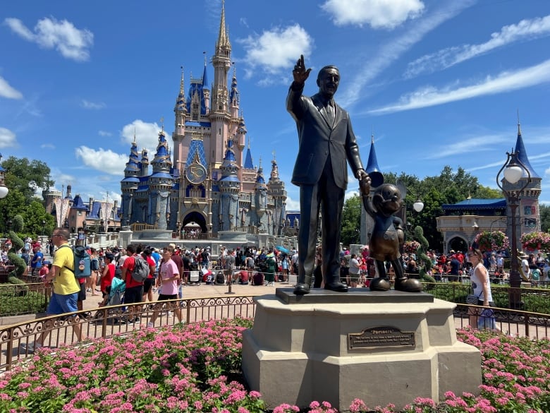 People walk behind a statue, with a castle in the background.