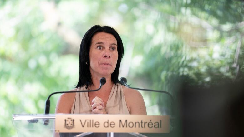 Valrie Plante wearing a beige halter top speaking at a podium that says 