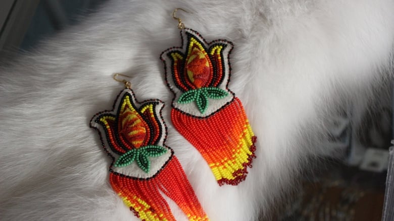 A pair of beaded and tufted earrings. They are in the shape of a flower, with petals made out of flames.