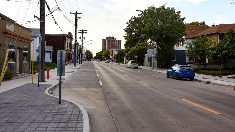 A quiet street with a couple of businesses on one side and small homes on the other.