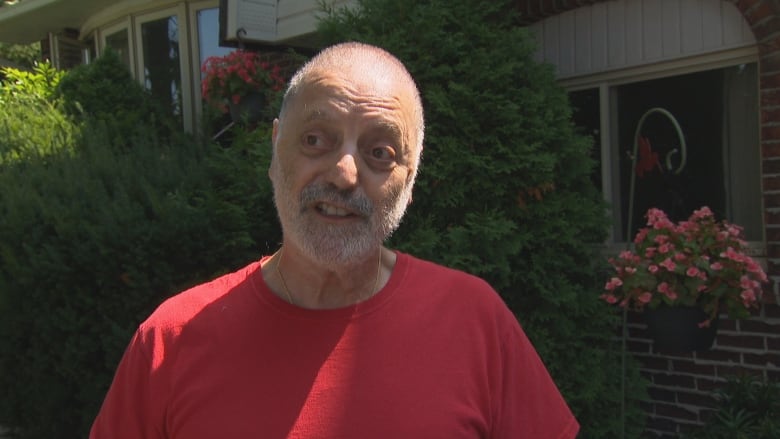 A man in a red shirt standing outside. 