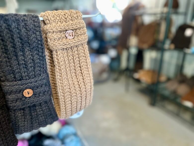 A brown and black knitted head band hangs on a rack in a store of other products. 