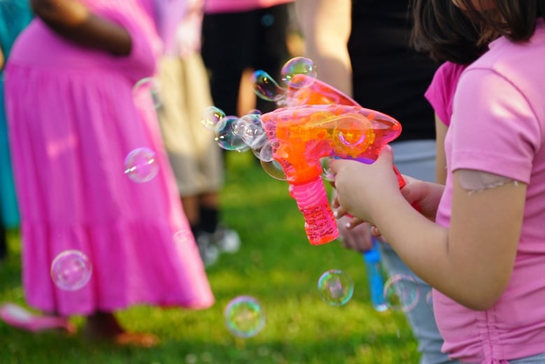 A girl from the local community holds two bubble guns at Anna Bielli's vigil on Wednesday.