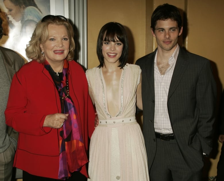 An older woman and a young man and young woman stand and pose for a photograph at an event. 