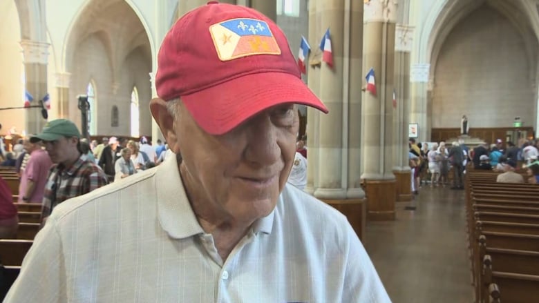 Man in red ball cap stands in a church.