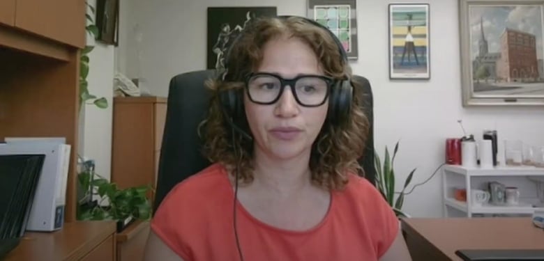 A person in glasses and a headset sits in an office