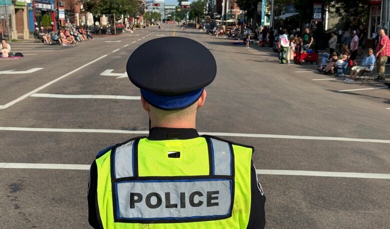 A police officer stands blocking off a street.