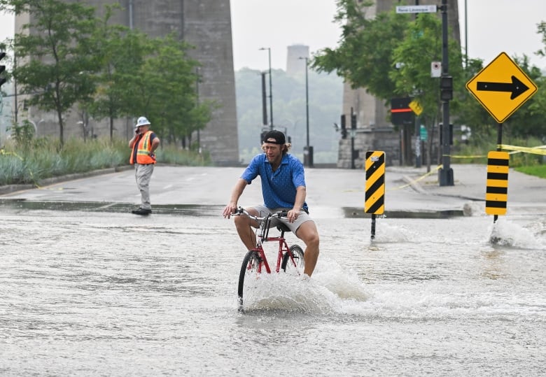 Man on bike lifting knees over flooded streets