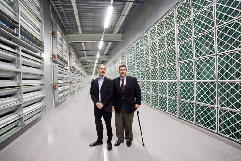 Two people in suits stand in a hallway of a new technology complex.