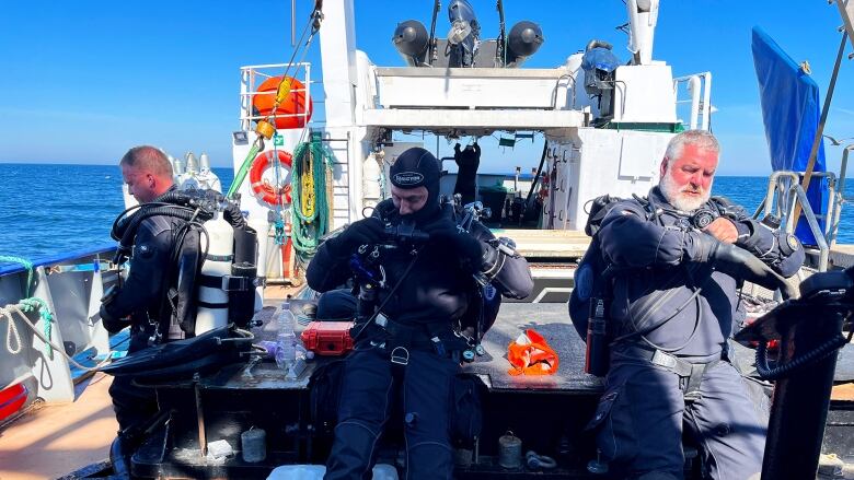 Three divers on a boat.