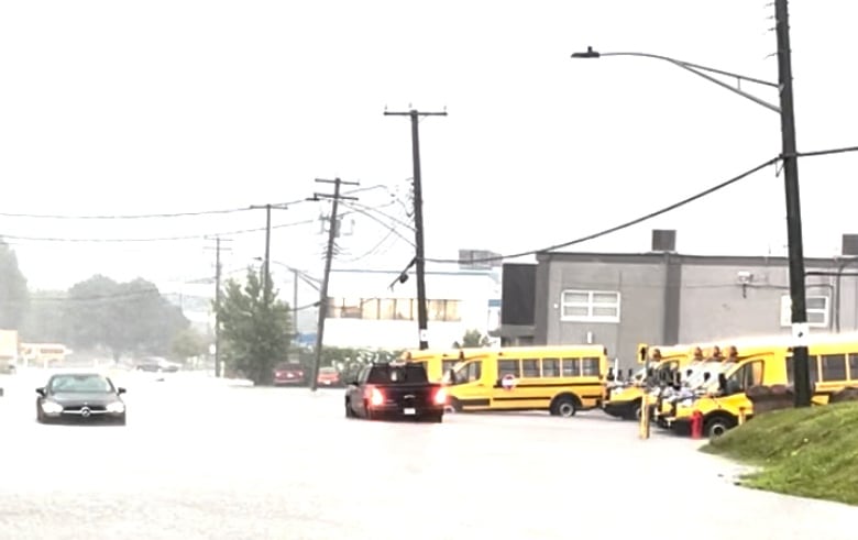 Flooded street with school buses and cars