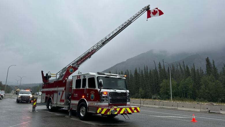 A bright red fire truck beside a smoky highway. 