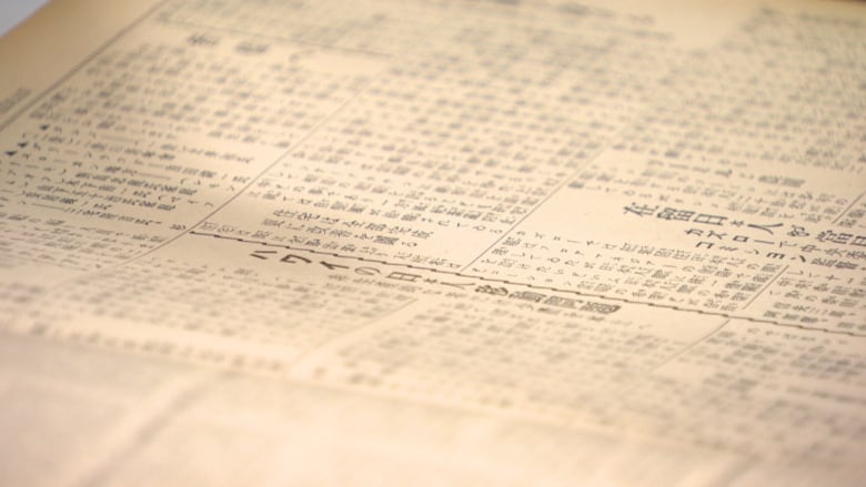 Up close shot of a newspaper with Japanese writing in a museum. 