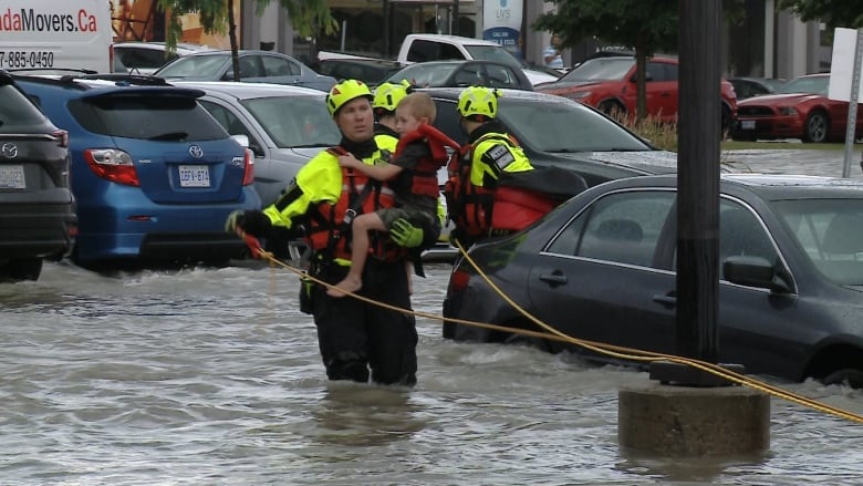 Photograph of a fireman holding a child, rescuing them in floodwater