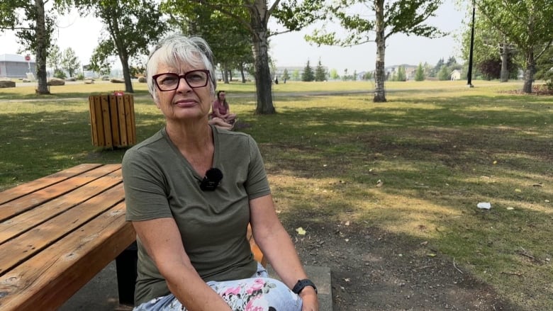 A woman sits on a bench in a park.