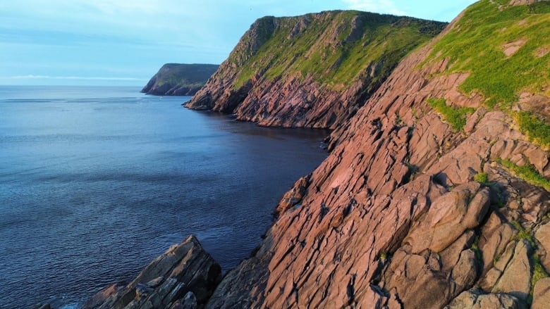 A sunrise over the a rocky cliff near the ocean.