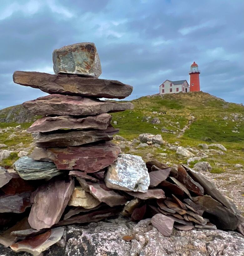 A lighthouse with a stone inukshuk nearby.