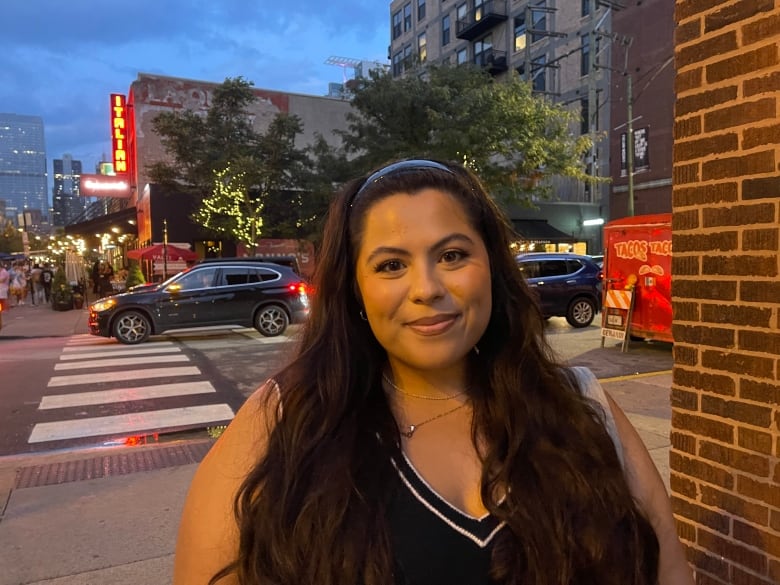 A woman stands on a downtown street.