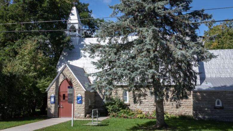 A stone church building that's been converted into a library, surrounded by trees on a sunny day.