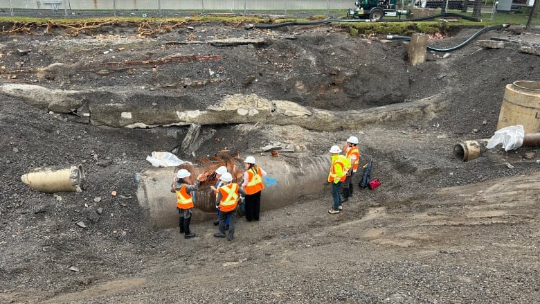 Crews are standing near a large water main.