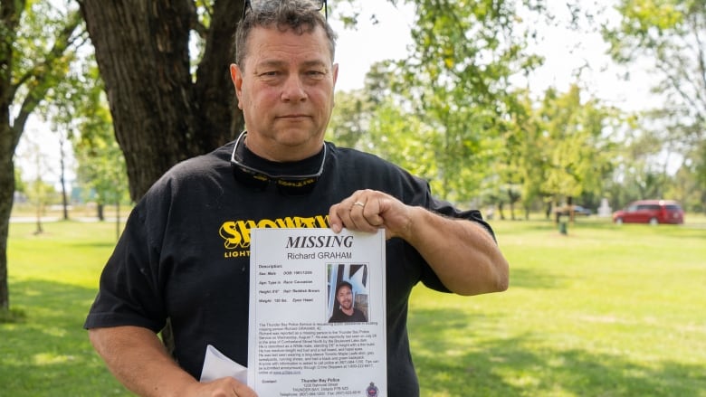 A man holds a missing person poster.