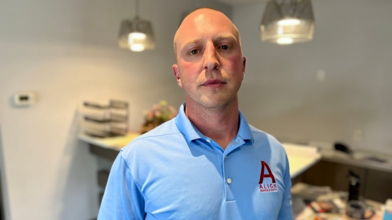 A man in a blue shirt looks at the camera