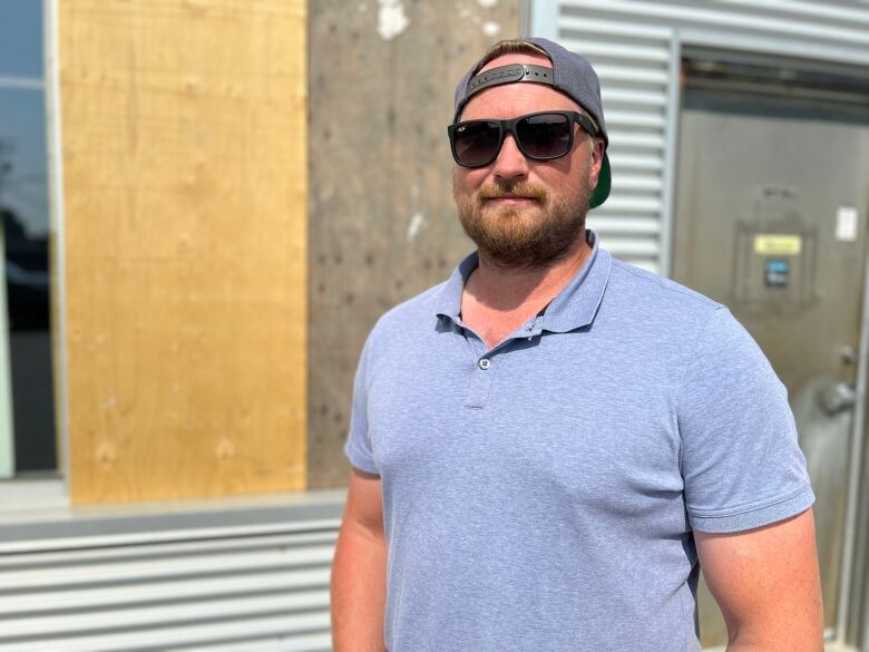 Man on a blue shirt stands in front of a business