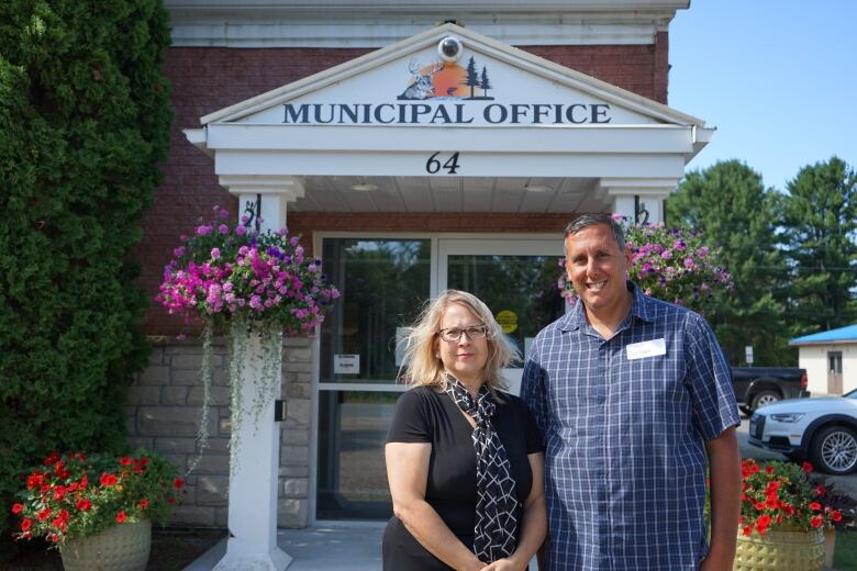 Two people pose for a portrait outside of a municipal building.