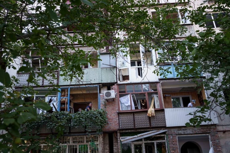 Residents of Pokrovsk, Ukraine, are seen clearing glass from their balconies on Tuesday, in the aftermath of Russian bombardment.