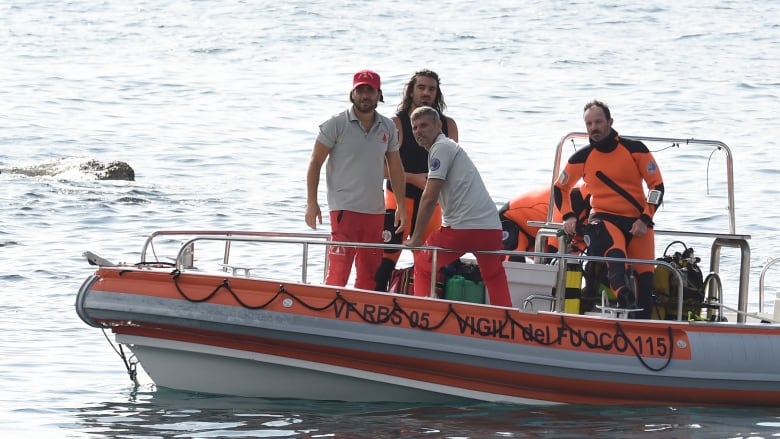 Several men standing in a small boat that is painted with neon orange. 