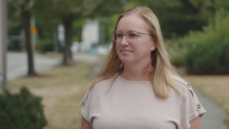 A woman in glasses looks at the camera.