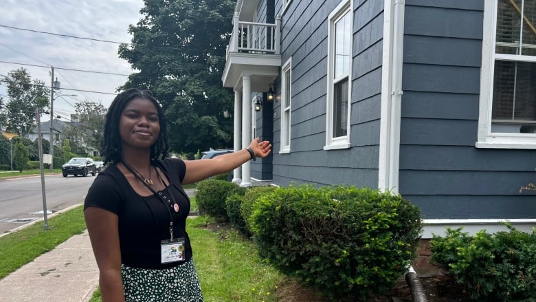 Black woman pointing to grey building.