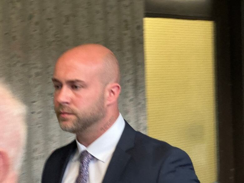 A balding man wearing a suit is seen in this photo taken at court.