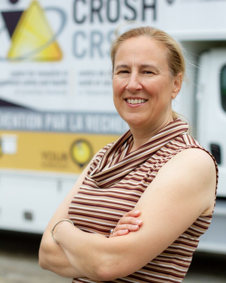 A smiling woman standing with her arms crossed.